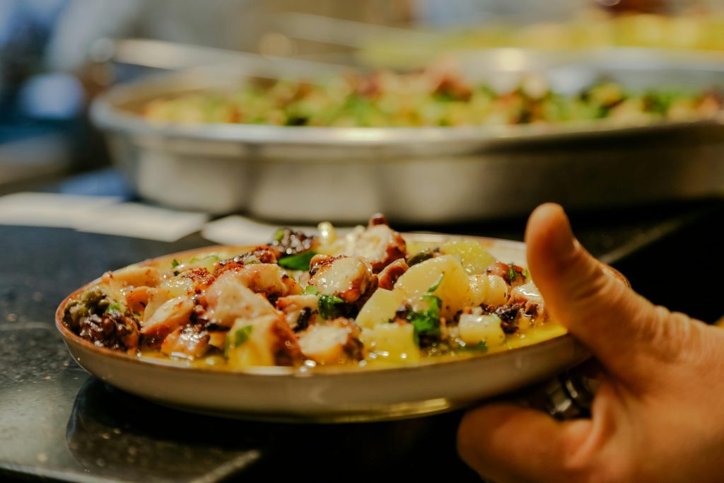 pexels-photo-20226303-20226303 A vibrant dish of octopus and potatoes garnished with herbs, presented on a ceramic plate.