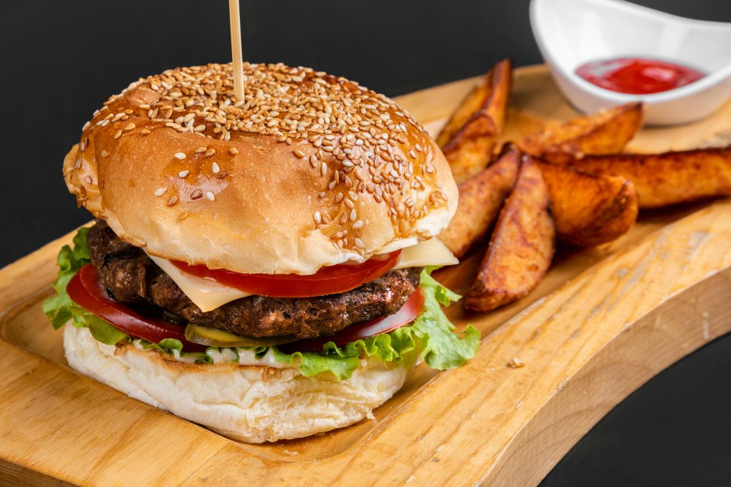 pexels-photo-3864682-3864682 Mouthwatering gourmet burger with fresh ingredients and crispy fries on a wooden platter.